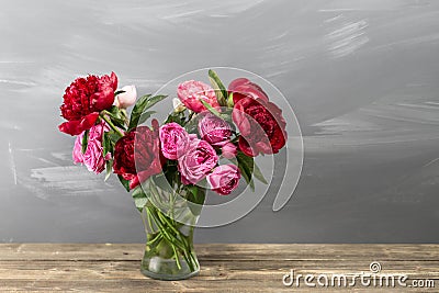 Red peonies and garden roses in vase. retro styled photo. close-up Stock Photo