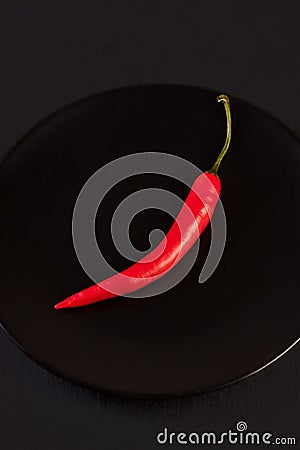 Red pepper on black plate Stock Photo