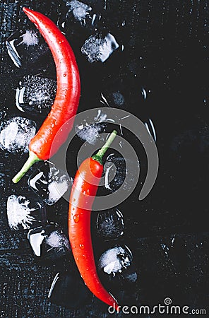 Red pepper and ice on a black wood background, fresh hot food on vintage table, freeze cold cube ice mock up top view Stock Photo