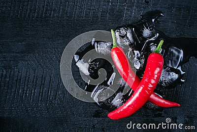 Red pepper and ice on a black wood background, fresh hot food on vintage table, freeze cold cube ice, mock up top view Stock Photo