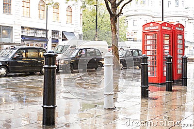 Red Phone cabines in London and vintage taxi.Rainy day. Editorial Stock Photo
