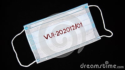 Red phrase VUI-202012 01 on a medical mask on a black background. The concept of medicine and coronavirus. Stock Photo