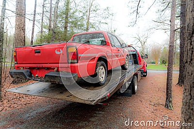 Red pickup truck being loaded on red tilt bed tow truck to be hauled away Stock Photo