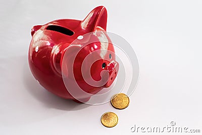 Red Piggy bank on a white table. Coin box with euro coins lying nearby. The concept of saving or save money or open a bank deposit Stock Photo