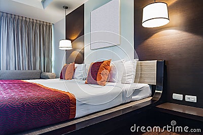 Red pillow on double bedroom with white bedsheet and lamp light Stock Photo