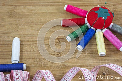 Red pincushion and several colourful threads as a sun and two treads as a boat Stock Photo