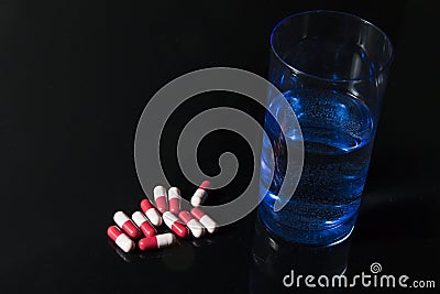 Red and pink antibiotic capsule and glass of water Stock Photo