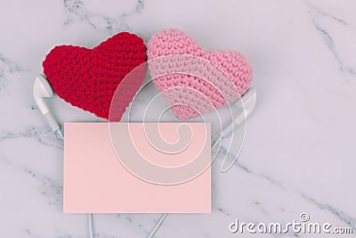 Red and pink hearts use headphone together with orange note on white marble background with copy space. Concept of couple, lover, Stock Photo