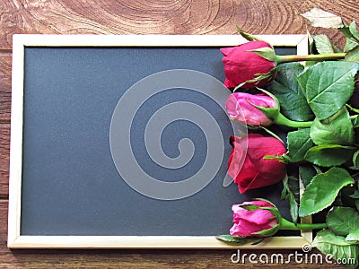 Red and pink roses placed on the blackboard on the wooden background Stock Photo