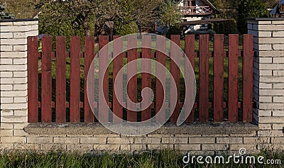 Red planks in a stone white fence around a house Stock Photo