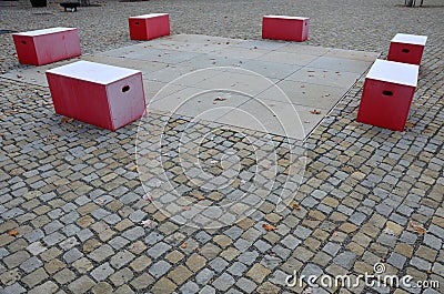 Red plastic benches in the shape of blocks with handles. The square is paved with granite cubes. sandy surface. built around a squ Stock Photo