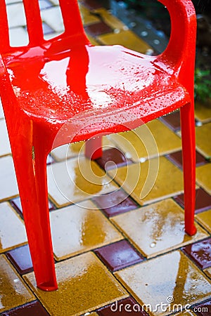 Red plastic garden chairs on the outdoor terrace in the home garden after the rain Stock Photo