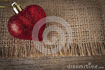 Red plastic heart placed on sack and wooden table Stock Photo