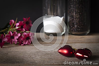 Red plastic hearts placed on a wooden table There is a flower placed on the left back and there are Stock Photo