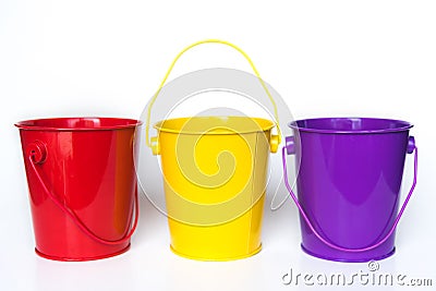 Three metal buckets colored red, yellow, and purple standing in row against solid white background Stock Photo