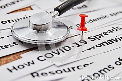 Red pushpin attached to inscription COVID-19 on the background of newspaper headline clippings and Stethoscope Stock Photo