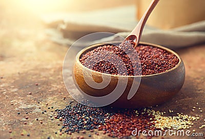 Red quinoa grains in a wooden spoon. Healthy food in a bowl. Seeds of white, red and black quinoa - Chenopodium quinoa Stock Photo