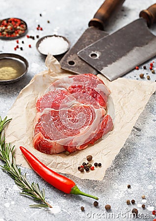 Red raw beef rib eye steak fillet with steel hatchets on light background with salt and pepper Stock Photo