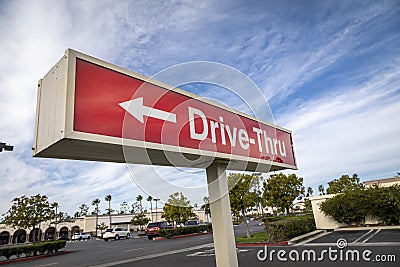 Red rectangular sign reading Drive Thru for fast food restaurant against blue sky and clouds Stock Photo