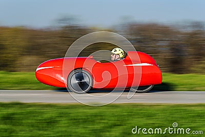 A red recumbent tricycle rushing by on a bikepath Editorial Stock Photo