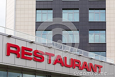 Red restaurant title on modern gray tiled building facade. Stock Photo