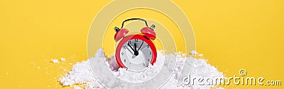 Red retro alarm clock with snow on yellow background. Creative Christmas or New year concept. Stock Photo