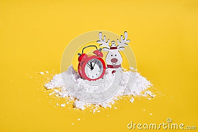 Red retro alarm clock with snow on yellow background. Creative Christmas or New year concept. Stock Photo