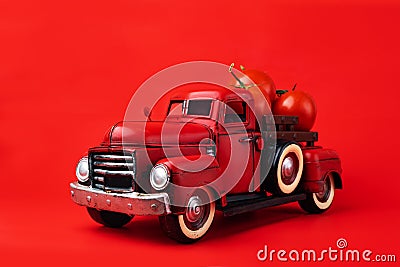 Red retro pickup truck carries fresh tomatoes on a red background, harvesting, and creative presentation of the product Stock Photo