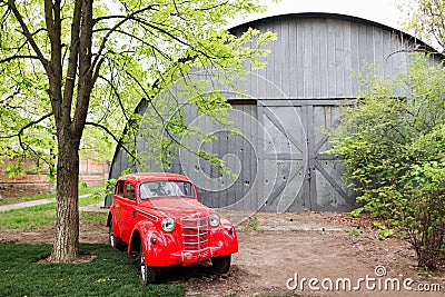 Red retro small vintage car standing in the garden in the summer Stock Photo