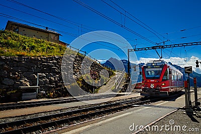 Red RhB train in Alp Grum railway station, Grisons, Switzerland. Editorial Stock Photo