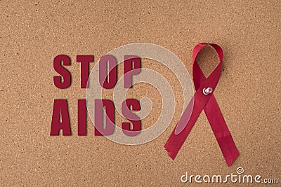 Red ribbon aids ribbon on notice board with `Stop Aids` word. Stock Photo