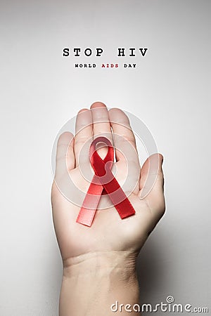 Red ribbon awareness on woman human hand aged white background: Stock Photo