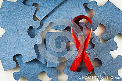 A red ribbon on a background of scattered jigsaw puzzles Stock Photo