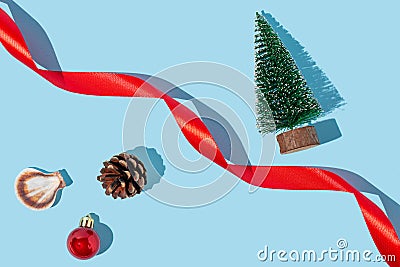 Red ribbon, seashell, pine cone, christmas tree and red christmas ornament ball on pastel blue background. Christmas holiday by Stock Photo