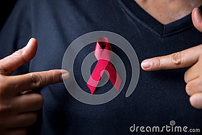 The red ribbon stick on black T-shirt. A person has a ribbon hang on shirt. The ribbon is the symbol of prevention HIV day. The Stock Photo