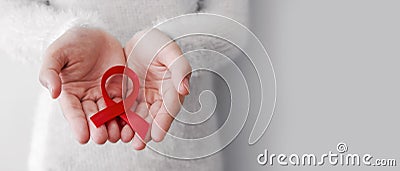 Red ribbon on woman hands for world aids day Stock Photo