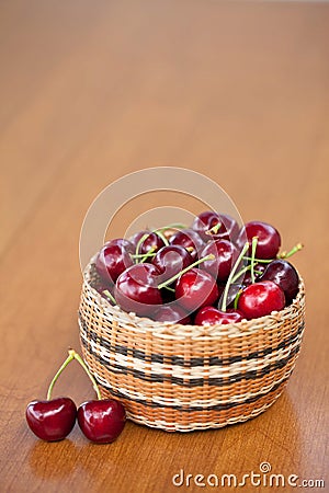 Red Ripe Cherries in a basket on a wood table Stock Photo