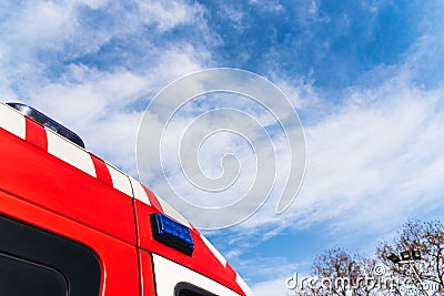Red roof of a medicalized ambulance over blue sky with clouds and copy space, to care for pandemic sufferers Stock Photo