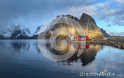 Red rorbuer and snowy rocks lighted by sun, blue sea at sunset Stock Photo