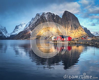 Red rorbuer and snowy rocks lighted by sun, blue sea at sunset Stock Photo