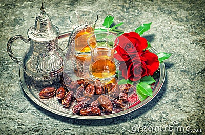 Red rose flowers with tea and dates fruits. Ramadan. Vintage sty Stock Photo