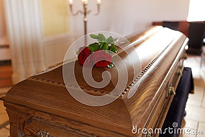 Red rose flowers on wooden coffin in church Stock Photo