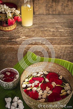 Red rose, Jasmine and popped rice on the calm water surface placed on the wood table Ready for pour water on the hands of revered Stock Photo