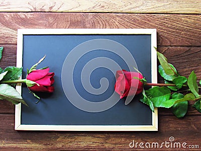 Red and pink roses placed on the blackboard on the wooden background. Valentine`s Day background Stock Photo