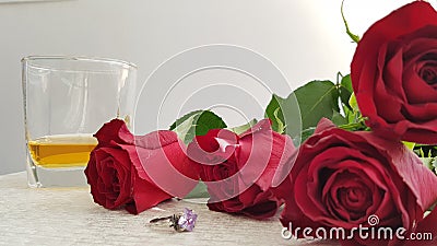 Red roses on white table near silver ring with big violet crystal Stock Photo