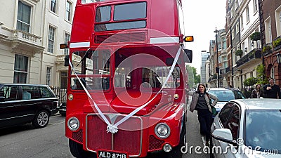 A red Routemaster bus on a London street with ribbon wedding celebration. Editorial Stock Photo