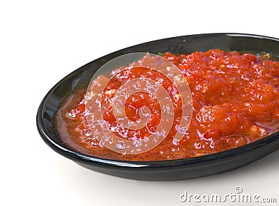 Red sauce on the black saucer isolated over white Stock Photo