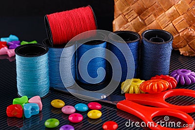 Red scissors, variety beads and spools of thread on glossy surface. Stock Photo
