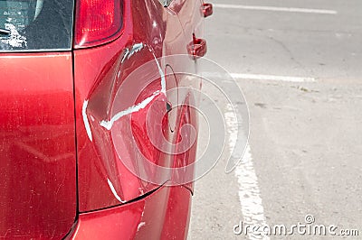 Red scratched car with damaged paint in crash accident or parking lot and dented damage of metal body from collision Stock Photo