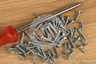 Red Screwdriver and Screws on a Wooden Table Stock Photo